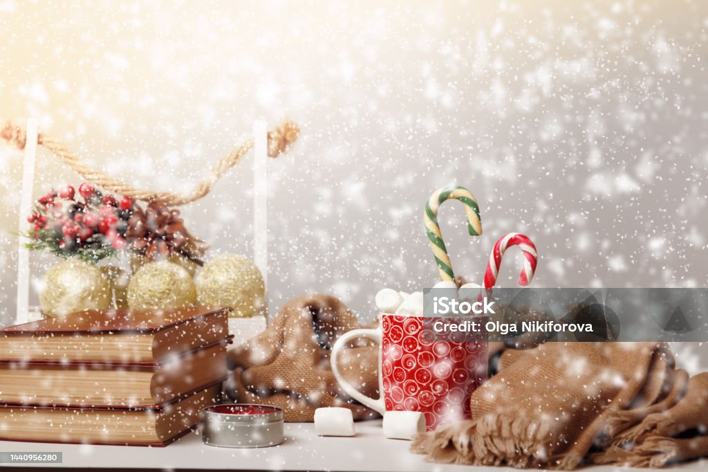 Joyeux Noël. Tasse avec des guimauves et pile de livres avec chute de neige floue.